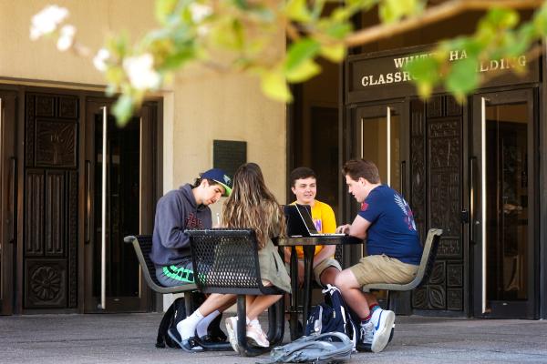 Photo of students sitting together at a table outside of White Hall Classroom Building