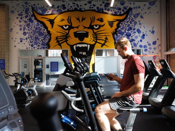 Photo of student sitting on exercise bike in Alumni Gym on campus